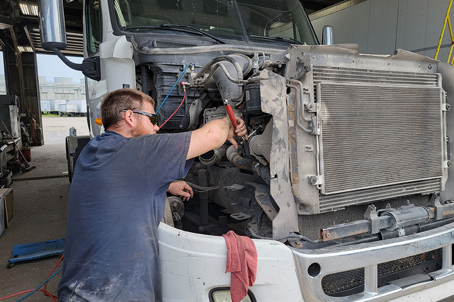 A professional DOT inspection technician repairing a broken part on a semi-truck in Decatur, IL to pass a federal vehicle inspection.