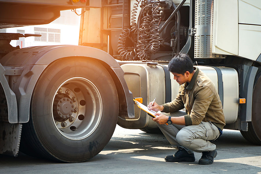 An auto mechanic checking a semi truck's safety maintenance checklist in Decatur, IL.