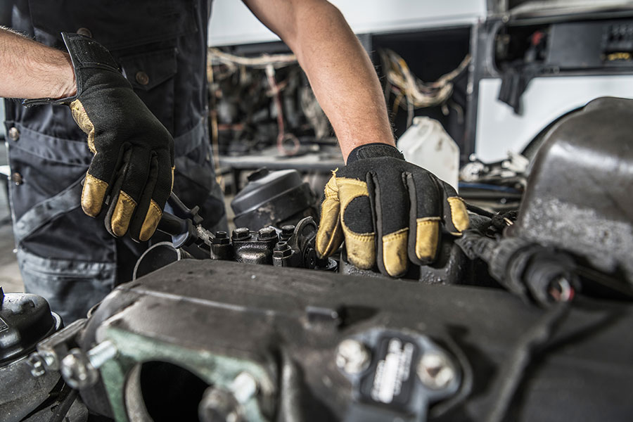 Close-up of a mechanic's hands repairing a diesel engine on a semi-truck.