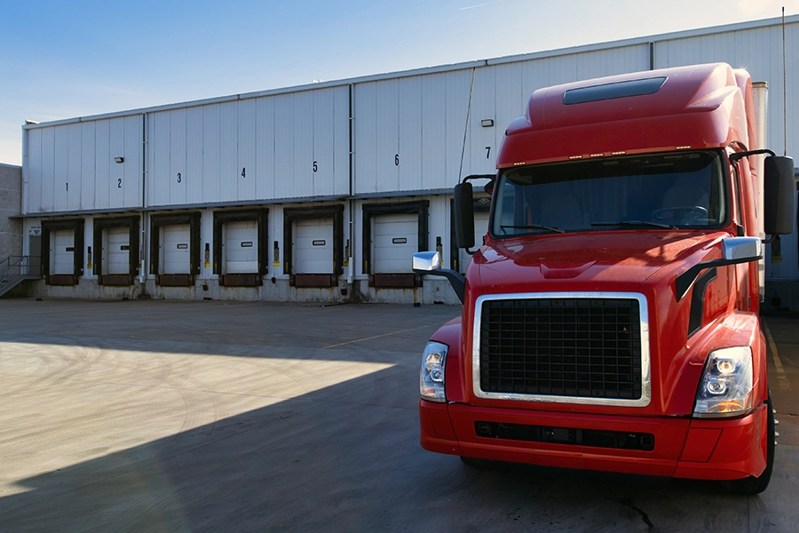 Red Semi-Truck at a loading dock in Decatur, IL, waiting to get loaded to help deliver packages to suppliers.