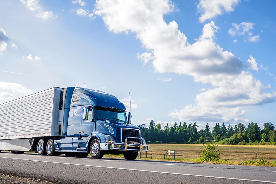 A blue semi-truck driving on a road near Decatur, IL, on its way to receive vehicle maintenance