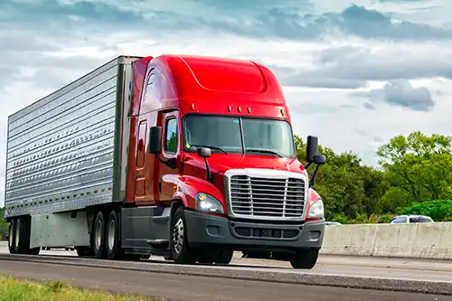 Decatur Trailer Sales & Service Inc.—A red semi-truck drives along a highway in Decatur, IL.