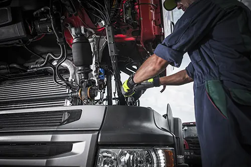 Decatur Trailer Sales & Service Inc. – Mechanic in Decatur, IL, using tools to work on repairing the transmission in a semi-truck.