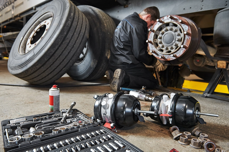 Mechanic at Decatur Trailer Sales & Service Inc. servicing the tires of a semi-truck in Decatur, IL, with tools behind him.
