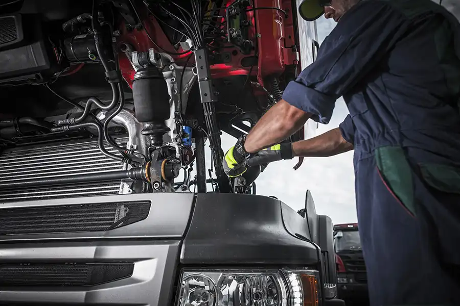 Decatur Trailer Sales & Service Inc. – Mechanic in Decatur, IL, using tools to work on repairing the transmission in a semi-truck.