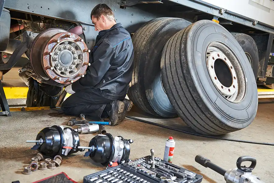 Decatur Trailer Sales & Service Inc. – Mechanic with tools sitting by him working on a brake repair on a semi-truck in Decatur, IL.