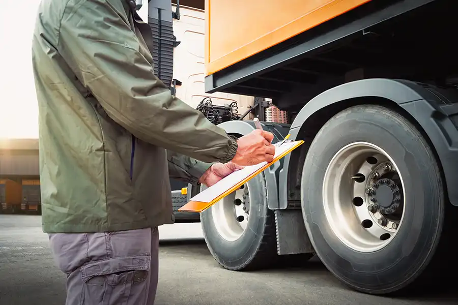 Decatur Trailer Sales & Service—A worker with a clipboard prepares to examine a semi-truck and perform professional maintenance services at a shop in Decatur, IL.