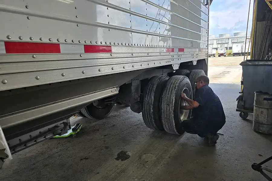 An auto mechanic at Decatur Trailer Sales & Service in Decatur, IL checking on semi-trailer tires.