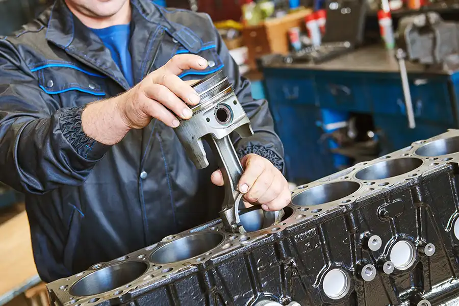 Decatur Trailer Sales & Service—An auto mechanic repairs a diesel truck engine by installing a piston in a garage in Decatur, IL.