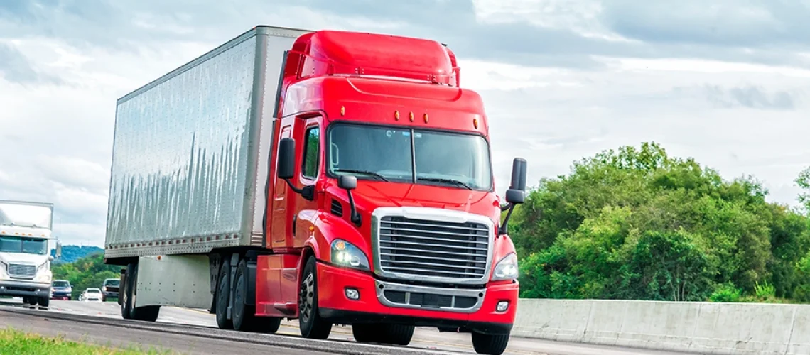 A red semi-truck driving in Decatur, IL, after having been inspected by Decatur Trailer Sales & Service.