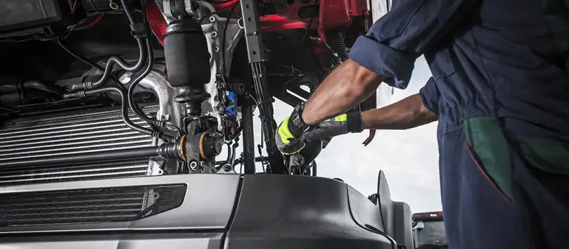 Decatur Trailer Sales & Service Inc. – Mechanic in Decatur, IL, using tools to work on repairing the transmission in a semi-truck.