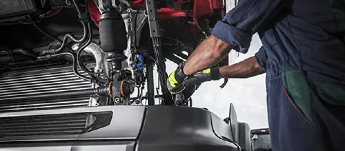 Decatur Trailer Sales & Service Inc. – Mechanic in Decatur, IL, using tools to work on repairing the transmission in a semi-truck.