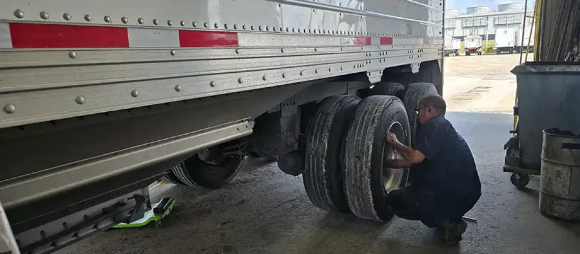 An auto mechanic at Decatur Trailer Sales & Service in Decatur, IL checking on semi-trailer tires.