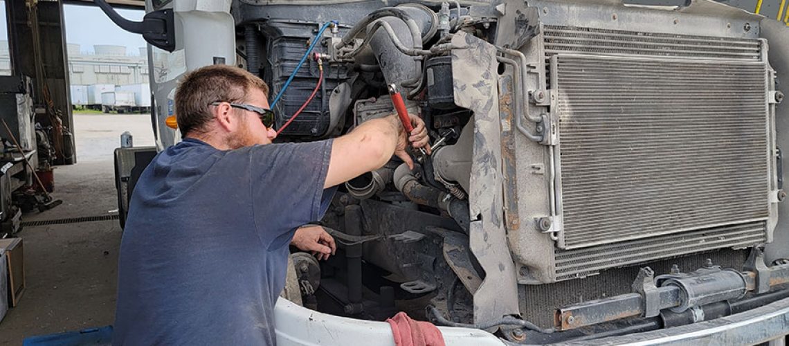 A professional DOT inspection technician repairing a broken part on a semi-truck in Decatur, IL to pass a federal vehicle inspection.