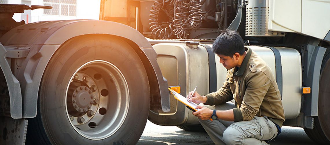 An auto mechanic checking a semi truck's safety maintenance checklist in Decatur, IL.