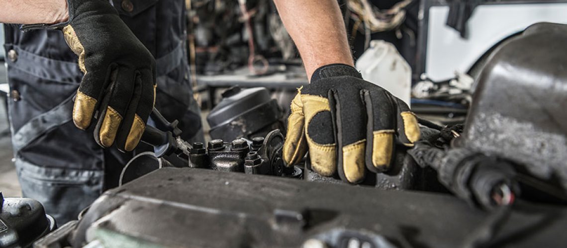 Close-up of a mechanic's hands repairing a diesel engine on a semi-truck.