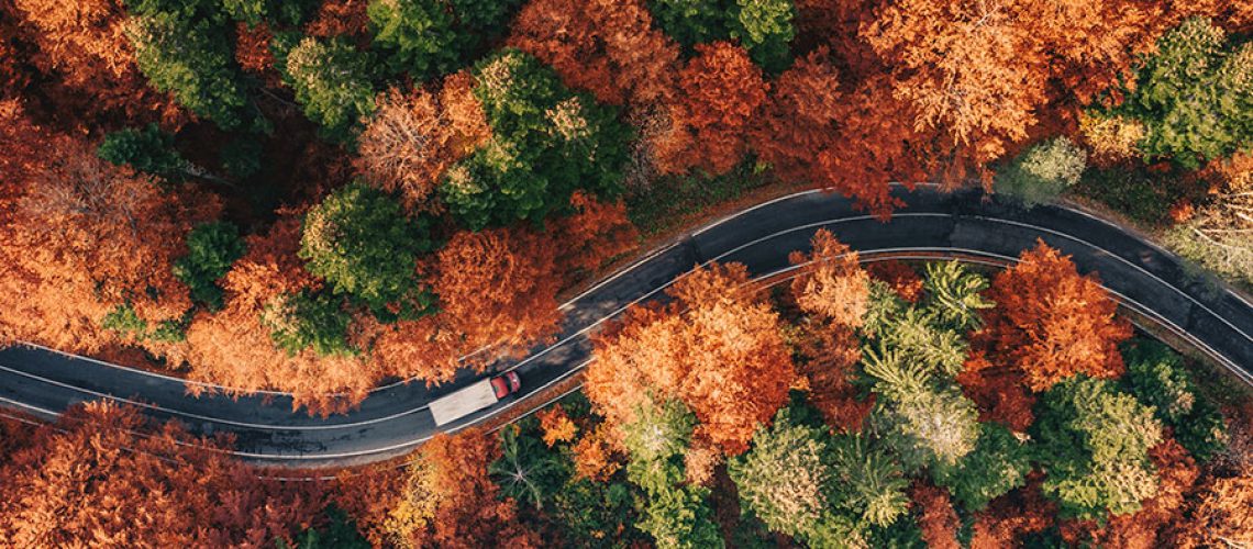 Winding road in autumn weather with truck driving on the road in Decatur, IL, surrounded by trees with orange leaves.